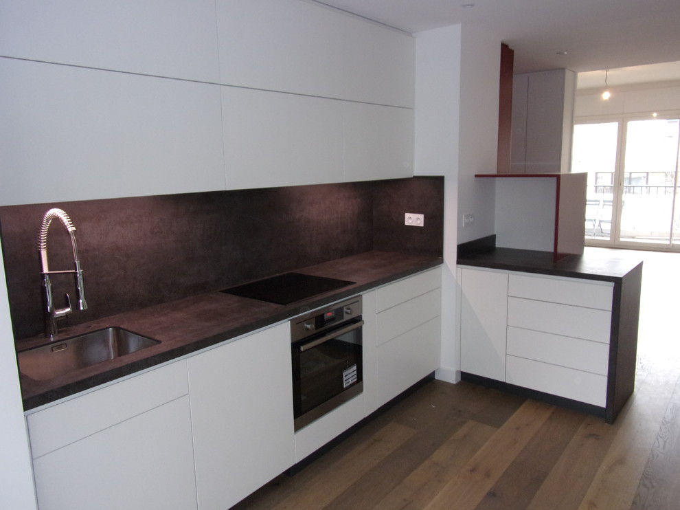 Contemporary l-shaped open plan kitchen in Marseille with a single-bowl sink, flat-panel cabinets and white cabinets.