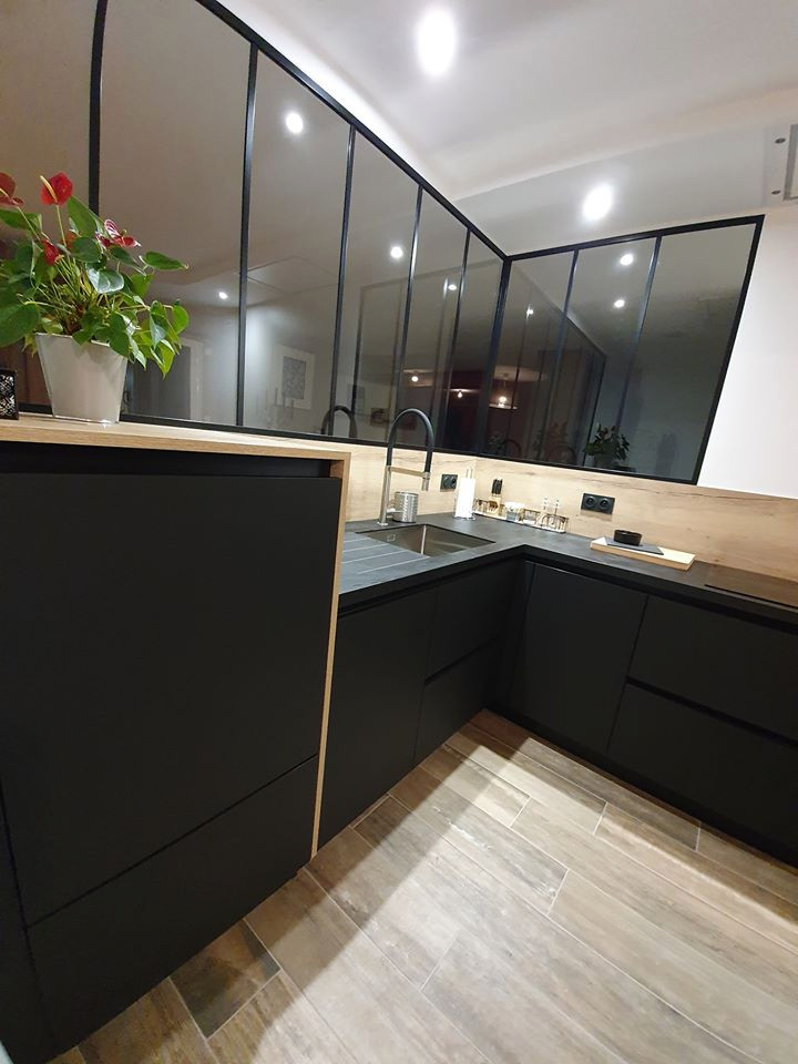 This is an example of a medium sized modern u-shaped open plan kitchen in Nantes with a submerged sink, flat-panel cabinets, black cabinets, laminate countertops, wood splashback, black appliances, light hardwood flooring, an island and black worktops.