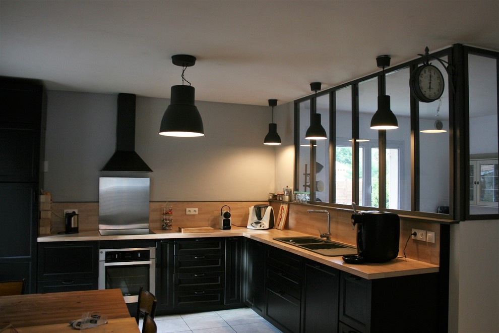 Inspiration for a large urban open plan kitchen in Bordeaux with an integrated sink, black cabinets, wood worktops, black splashback, wood splashback, stainless steel appliances, cement flooring, multiple islands and white floors.
