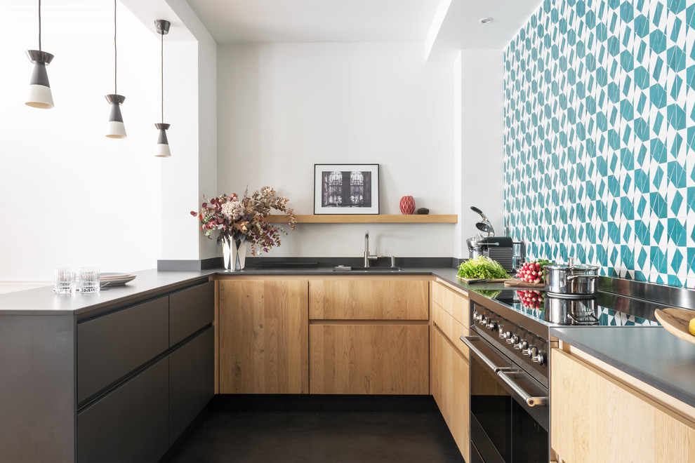 Exempel på ett skandinaviskt grå grått u-kök, med släta luckor, skåp i ljust trä, flerfärgad stänkskydd, en halv köksö och svart golv