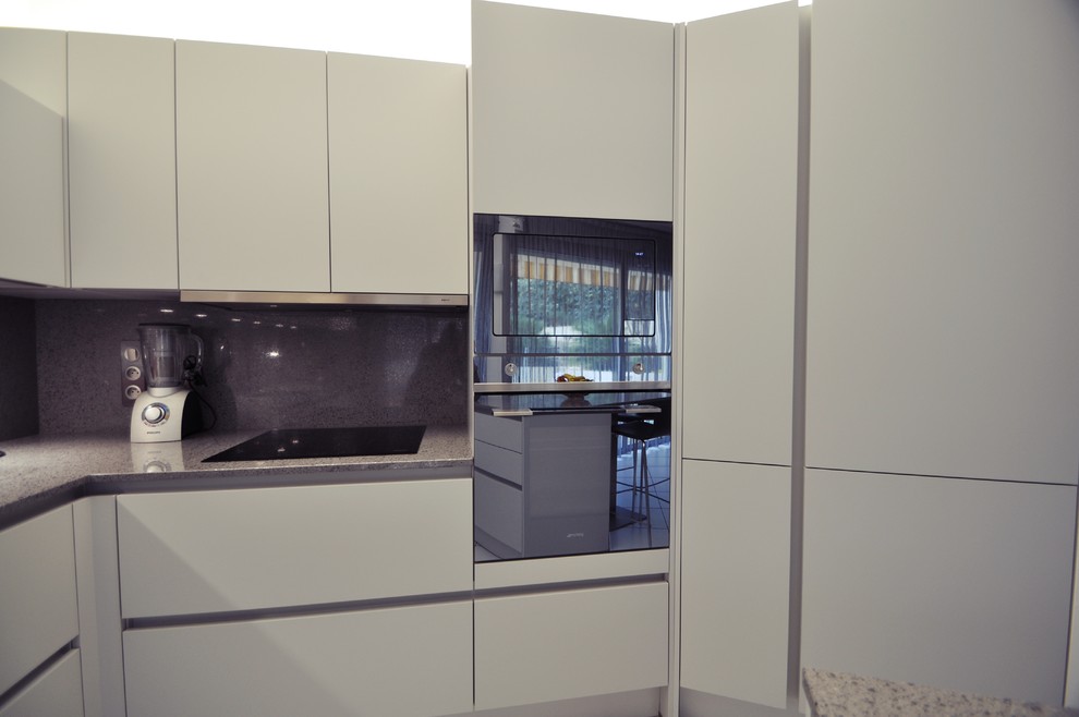 Пример оригинального дизайна: угловая кухня среднего размера в стиле кантри с монолитной мойкой, серым фартуком, черной техникой, полом из керамической плитки и островом