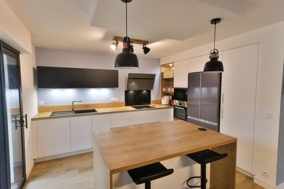 Immagine di una cucina minimal di medie dimensioni con lavello sottopiano, ante in legno chiaro, top in legno, paraspruzzi nero, paraspruzzi con piastrelle di vetro, elettrodomestici da incasso, pavimento beige e top beige
