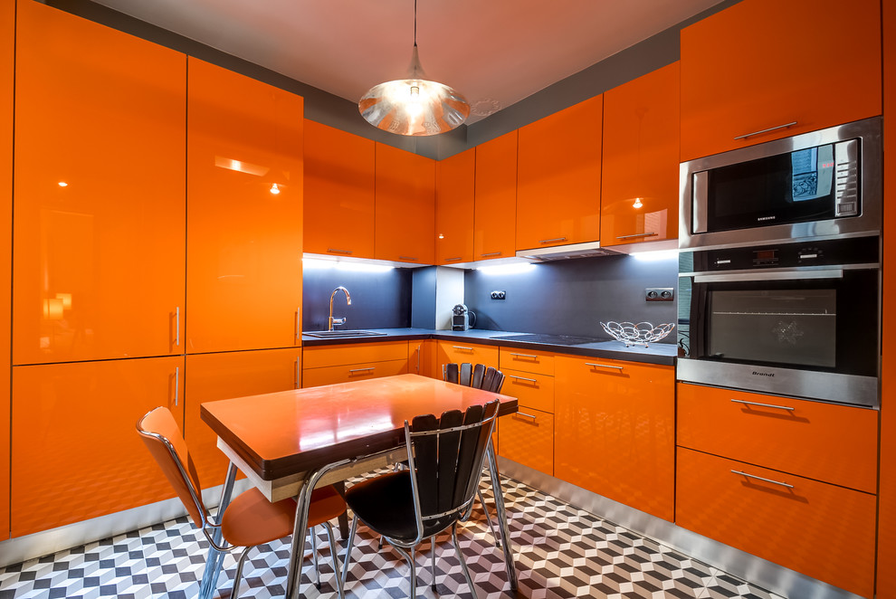 Cette image montre une cuisine américaine design en L de taille moyenne avec un évier encastré, des portes de placard oranges, un électroménager en acier inoxydable et un sol en carrelage de céramique.