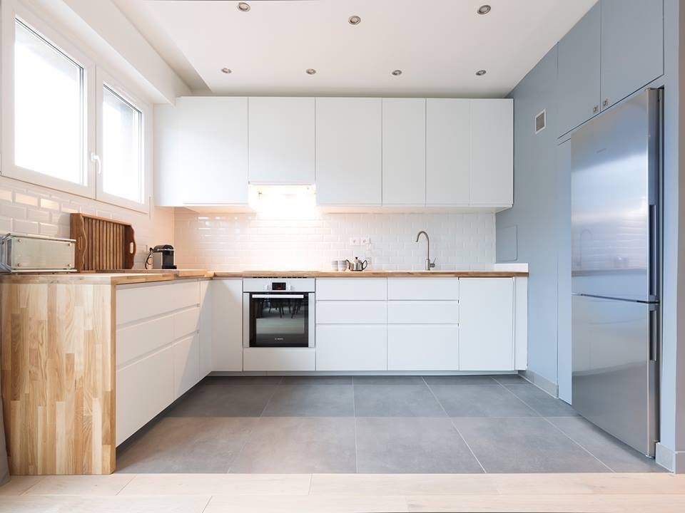 Design ideas for a medium sized contemporary l-shaped open plan kitchen in Paris with a submerged sink, beaded cabinets, white cabinets, wood worktops, white splashback, metro tiled splashback, white appliances, ceramic flooring, no island and grey floors.