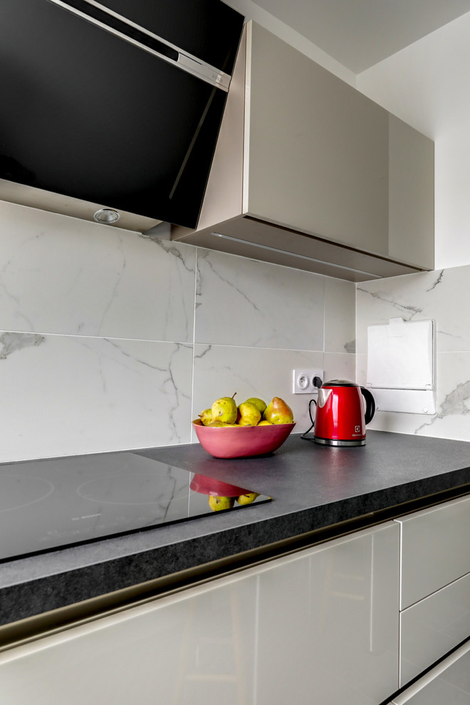 Bild på ett funkis kök, med en enkel diskho, skåp i rostfritt stål, marmorbänkskiva, rostfria vitvaror och svart golv