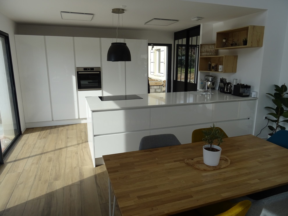 Photo of a large modern galley open plan kitchen in Marseille with an integrated sink, beaded cabinets, white cabinets, quartz worktops, stainless steel appliances, ceramic flooring, a breakfast bar, beige floors and white worktops.
