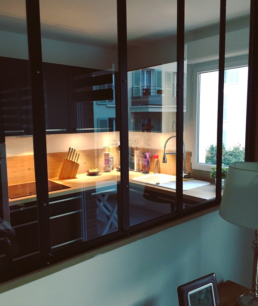 パリにあるお手頃価格の小さなモダンスタイルのおしゃれなキッチン (アンダーカウンターシンク、ラミネートカウンター、木材のキッチンパネル、パネルと同色の調理設備、アイランドなし、インセット扉のキャビネット、ステンレスキャビネット、茶色いキッチンパネル) の写真