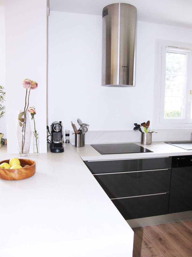Foto på ett mellanstort funkis vit kök, med luckor med profilerade fronter, ljust trägolv, brunt golv, en enkel diskho, svarta skåp, laminatbänkskiva, grått stänkskydd och rostfria vitvaror
