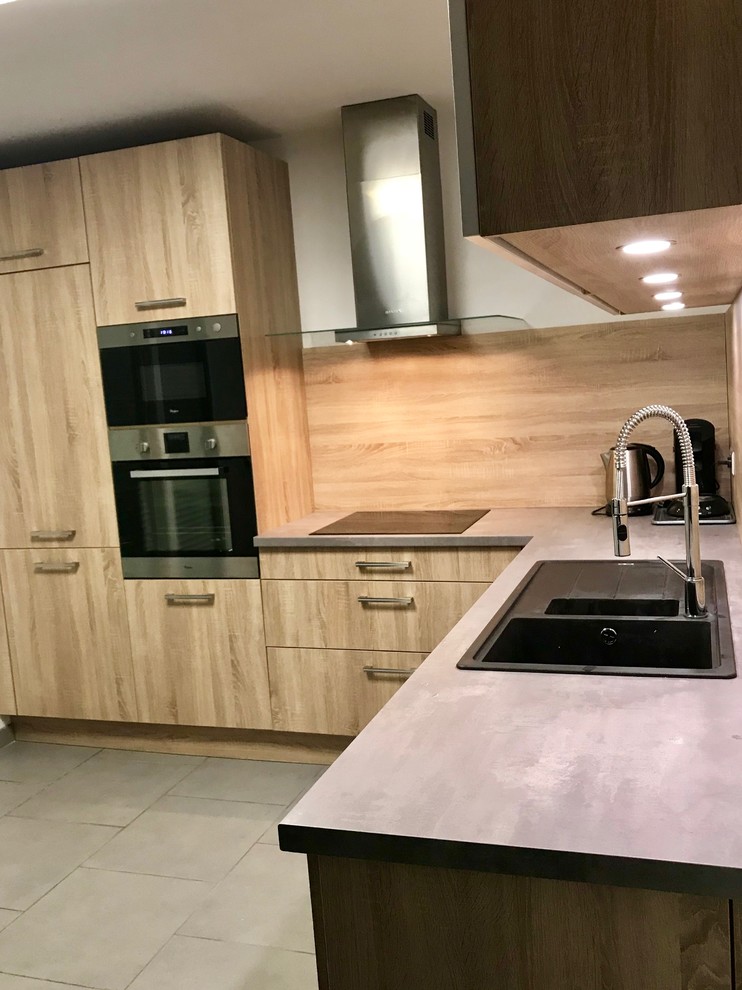 Modern inredning av ett avskilt, mellanstort l-kök, med skåp i ljust trä, laminatbänkskiva, rostfria vitvaror och grått golv