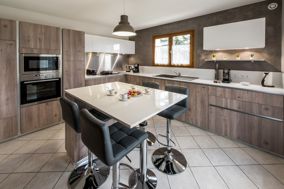 Réalisation d'une grande cuisine design en L et bois clair avec un plan de travail en granite, une crédence blanche, îlot, un placard à porte plane, un électroménager noir et un sol blanc.