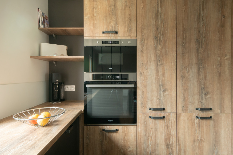 Idée de décoration pour une cuisine ouverte encastrable et bicolore urbaine en U et bois clair de taille moyenne avec un évier encastré, un placard à porte affleurante, un plan de travail en bois, un sol en carrelage de céramique, une péninsule, un sol gris et un plan de travail beige.