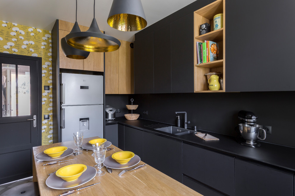 Inspiration for a large contemporary grey and black galley enclosed kitchen in Paris with an integrated sink, black splashback, stainless steel appliances, an island, grey floors and black worktops.