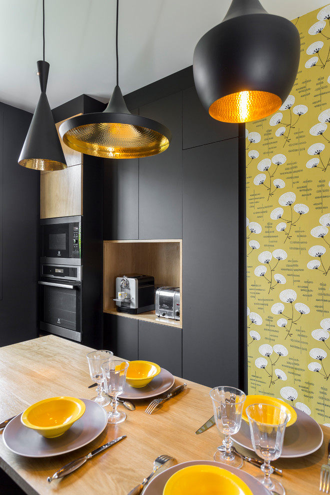 Immagine di una grande cucina design chiusa con lavello integrato, paraspruzzi nero, elettrodomestici in acciaio inossidabile, pavimento grigio e top nero