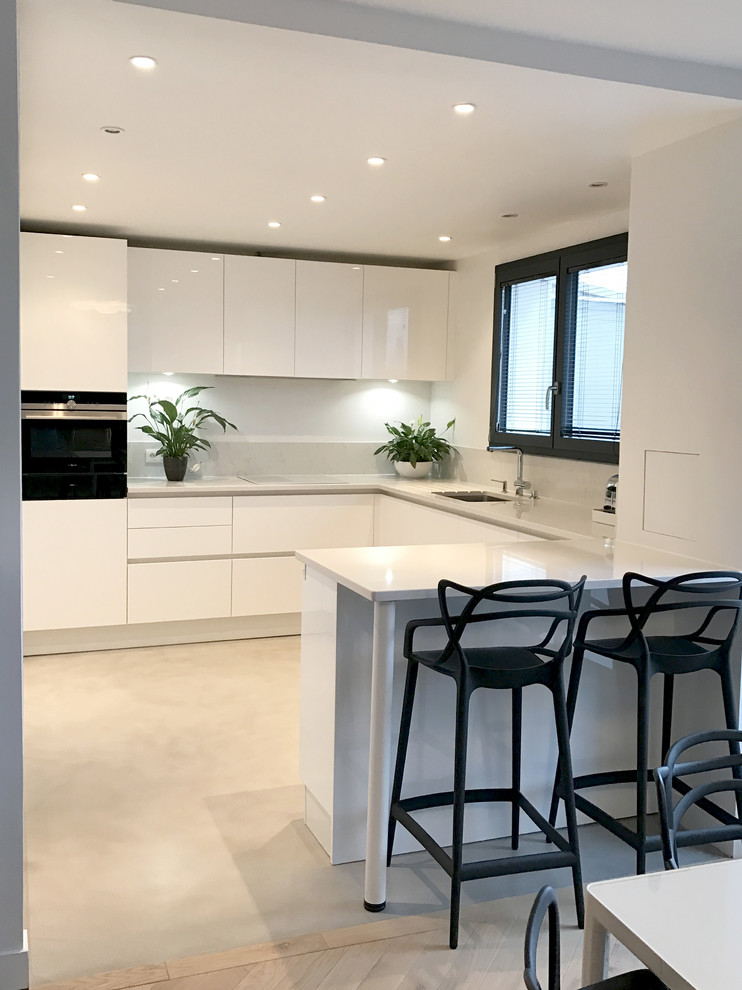 Foto di una cucina moderna di medie dimensioni con lavello sottopiano, ante bianche, elettrodomestici bianchi, pavimento in cemento e pavimento grigio
