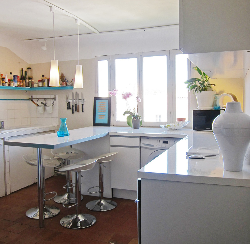 На фото: п-образная кухня среднего размера в средиземноморском стиле с обеденным столом, врезной мойкой, белыми фасадами, столешницей из ламината, белым фартуком, фартуком из керамической плитки, белой техникой и островом
