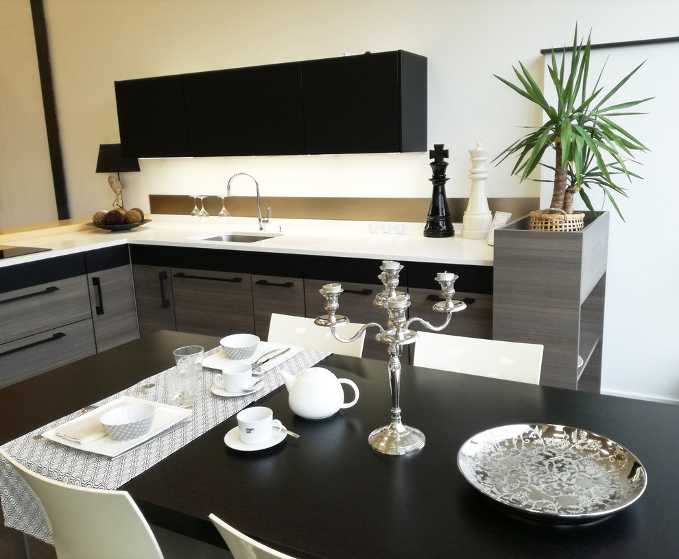 На фото: большая угловая кухня-гостиная в стиле модернизм с черными фасадами, столешницей из кварцита, фартуком цвета металлик и фартуком из стеклянной плитки