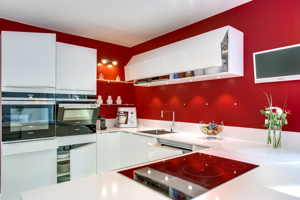 Mittelgroße Moderne Wohnküche in U-Form mit Unterbauwaschbecken, flächenbündigen Schrankfronten, weißen Schränken, Küchenrückwand in Rosa und weißen Elektrogeräten in Paris