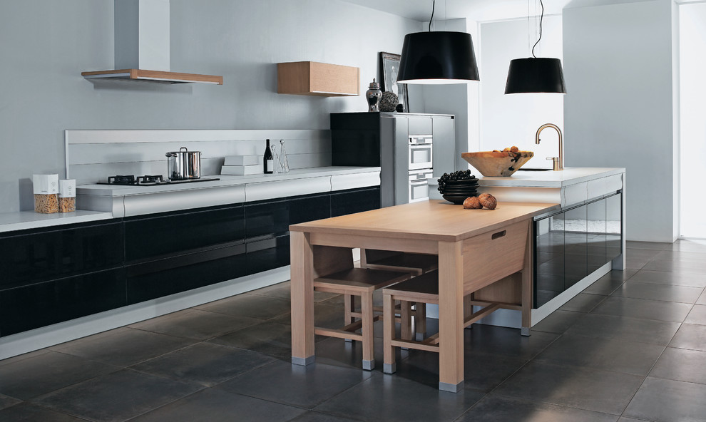 Cette image montre une grande cuisine ouverte parallèle design avec des portes de placard noires, une crédence grise, un électroménager en acier inoxydable et îlot.