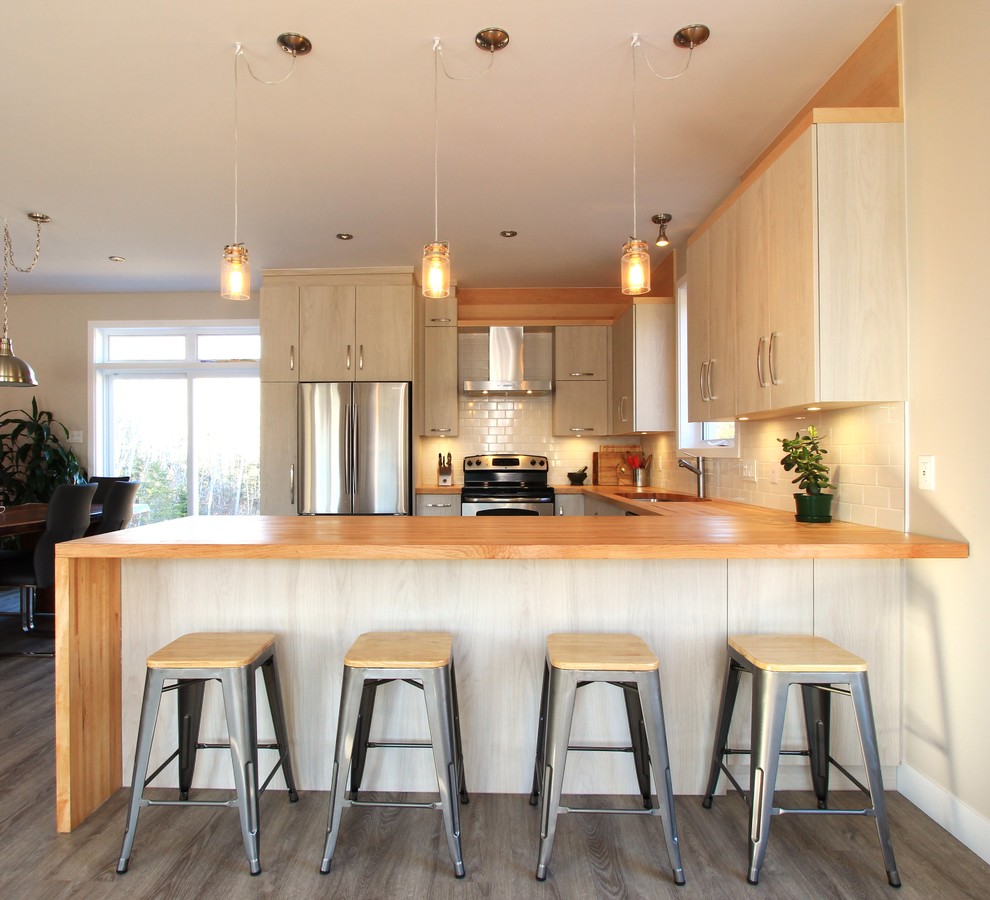 Foto på ett minimalistiskt kök, med en undermonterad diskho, släta luckor och en halv köksö
