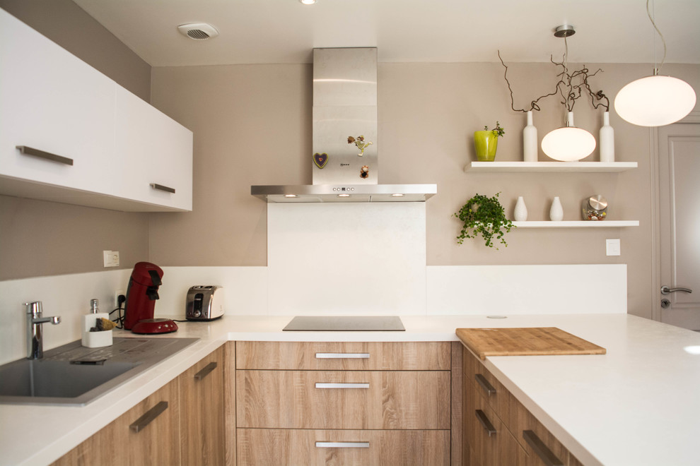 Photo of a small modern u-shaped kitchen/diner in Angers with a single-bowl sink, white splashback, stainless steel appliances, a breakfast bar and light wood cabinets.