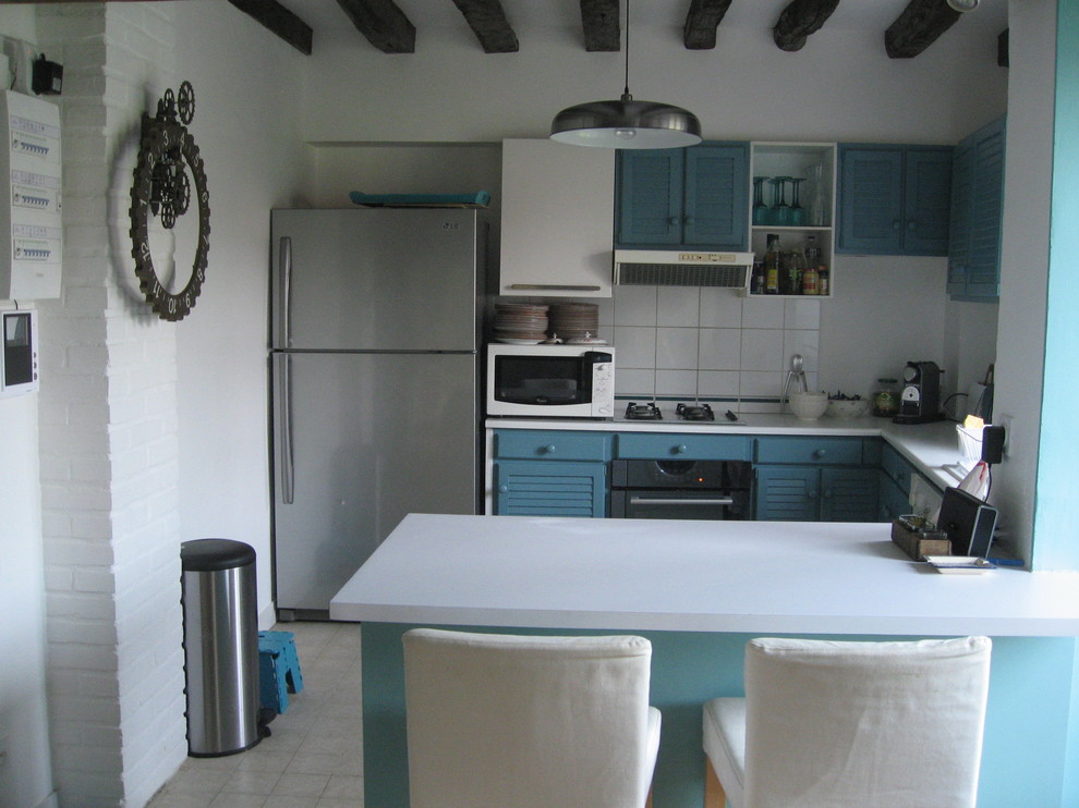 Cette photo montre une cuisine ouverte nature en U avec un placard à porte persienne, des portes de placard bleues, un plan de travail en stratifié, une crédence blanche et une crédence en carreau de porcelaine.