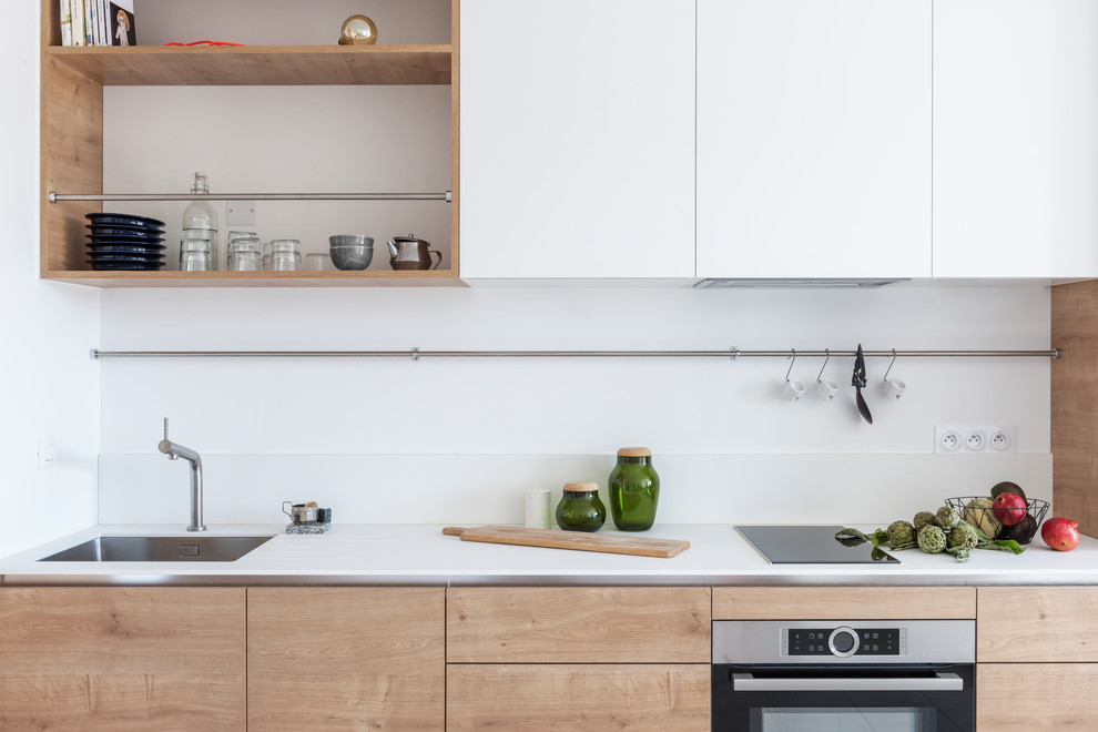 Ejemplo de cocina lineal escandinava de tamaño medio abierta sin isla con armarios con rebordes decorativos, fregadero de un seno, puertas de armario de madera oscura, salpicadero blanco, electrodomésticos negros, suelo beige y encimeras blancas