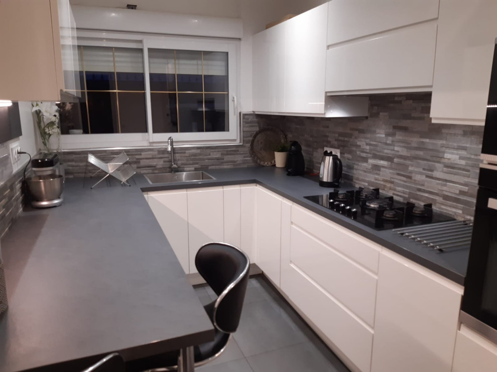 Inredning av ett modernt mellanstort grå grått kök, med en undermonterad diskho, luckor med profilerade fronter, vita skåp, laminatbänkskiva, grått stänkskydd, stänkskydd i kalk, integrerade vitvaror, grått golv och cementgolv