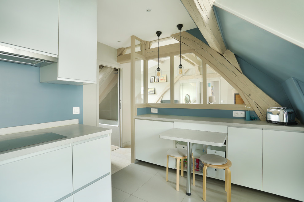 This is an example of a large scandi u-shaped enclosed kitchen in Paris with a submerged sink, beaded cabinets, white cabinets, laminate countertops, blue splashback, stainless steel appliances, ceramic flooring, grey floors and grey worktops.