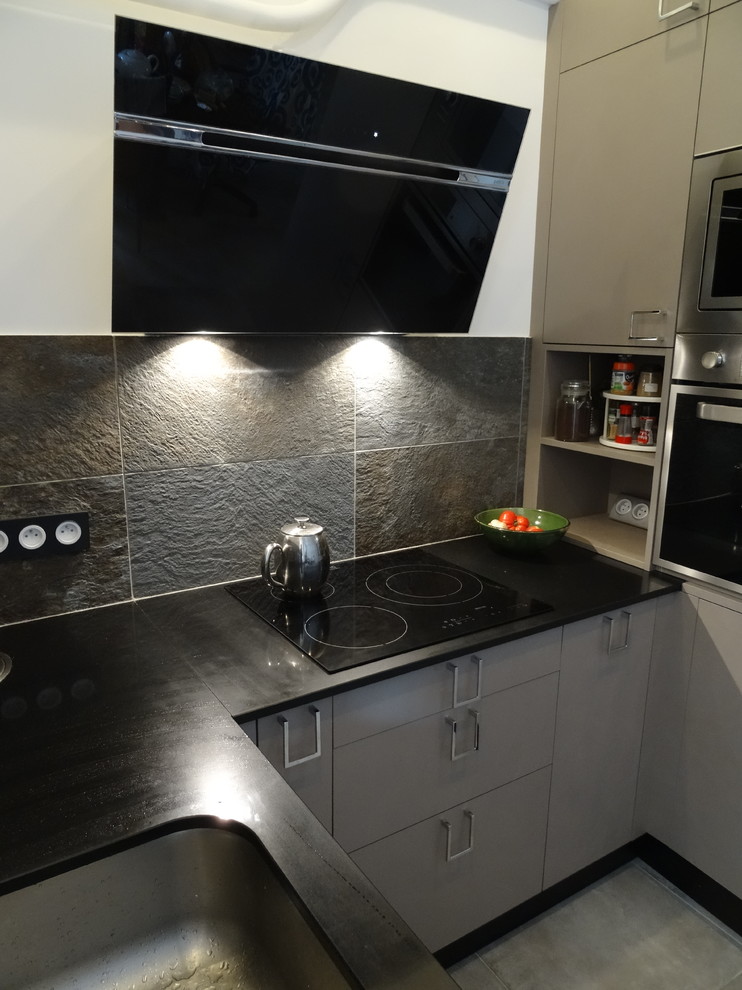 Exempel på ett litet industriellt svart svart kök, med en enkel diskho, luckor med profilerade fronter, bruna skåp, bänkskiva i kvartsit, grått stänkskydd, stänkskydd i skiffer, rostfria vitvaror, klinkergolv i keramik och grått golv