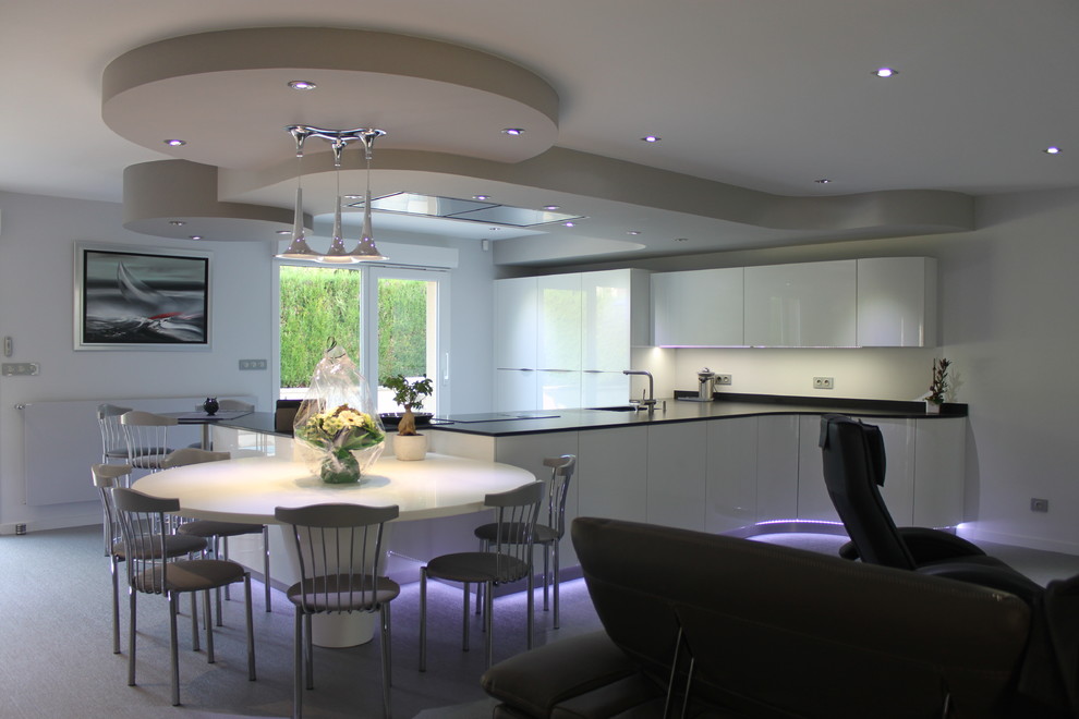 Large modern l-shaped open plan kitchen in Nancy with a single-bowl sink, light wood cabinets, granite worktops, white splashback, stainless steel appliances and an island.