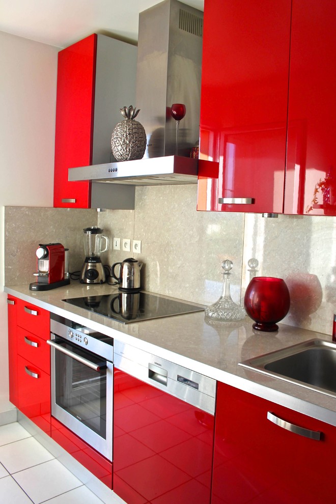 Imagen de cocina contemporánea pequeña cerrada con fregadero bajoencimera, armarios con paneles lisos, puertas de armario rojas y electrodomésticos de acero inoxidable