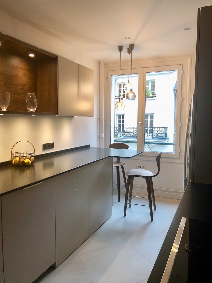 Medium sized contemporary galley enclosed kitchen in Paris with an integrated sink, beaded cabinets, beige cabinets, granite worktops, white splashback, ceramic flooring, beige floors and black worktops.