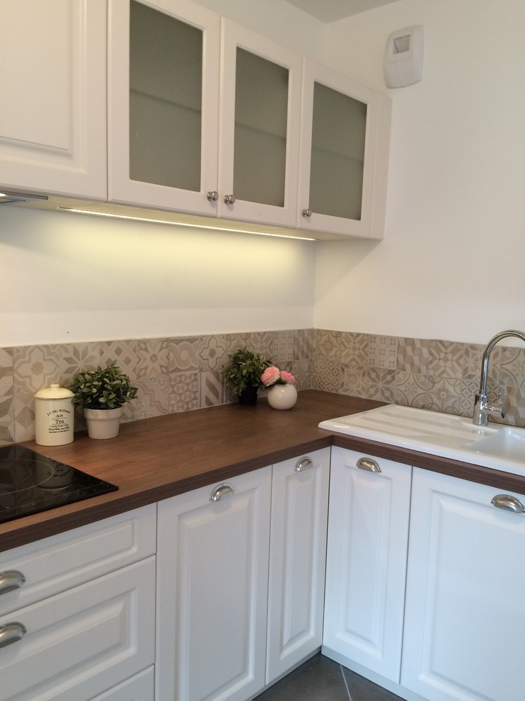 Small classic l-shaped open plan kitchen in Lyon with a submerged sink, wood worktops, beige splashback, cement tile splashback, stainless steel appliances, ceramic flooring, no island, beaded cabinets and stainless steel cabinets.