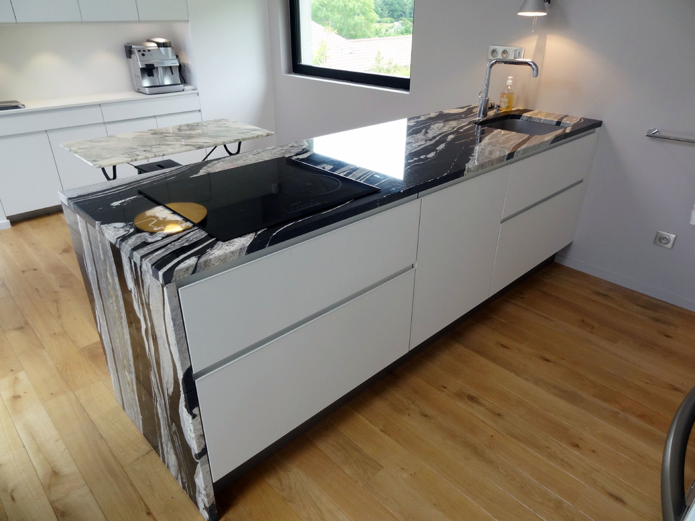 Offene, Zweizeilige, Mittelgroße Moderne Küche mit Waschbecken, Granit-Arbeitsplatte, Küchengeräten aus Edelstahl und hellem Holzboden in Lyon