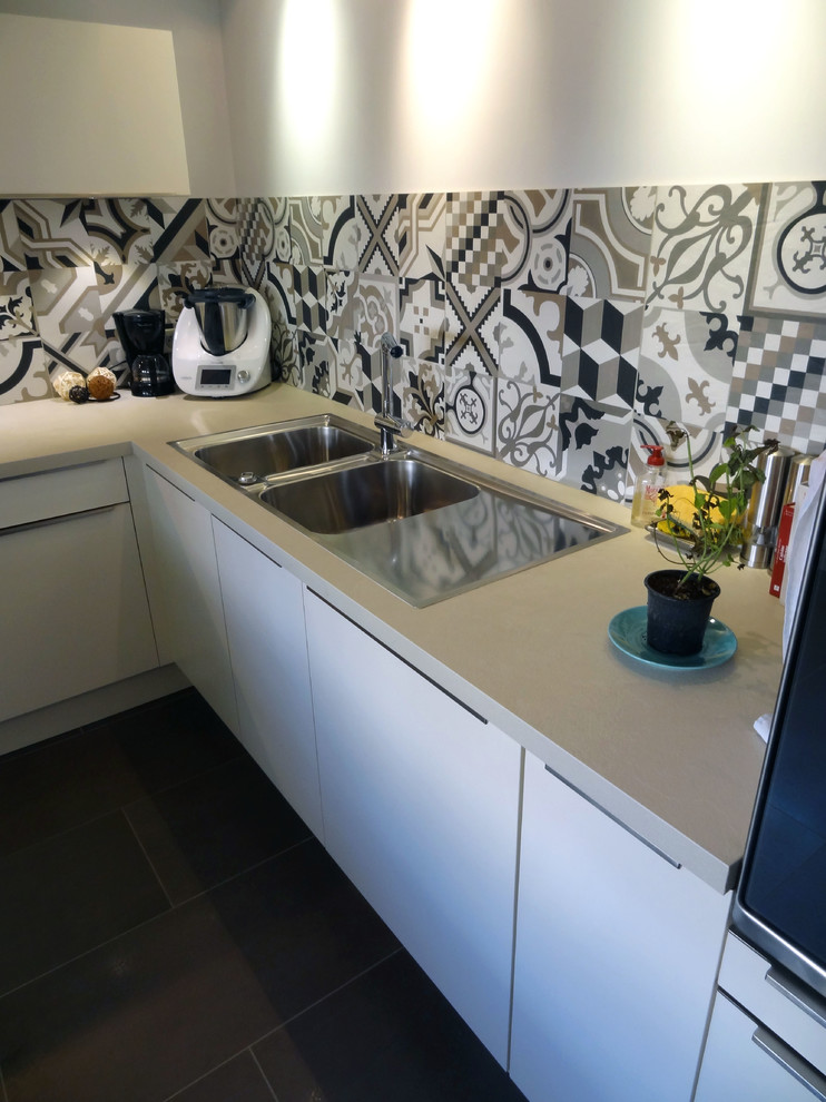Стильный дизайн: угловая кухня-гостиная среднего размера в современном стиле с двойной мойкой, столешницей из ламината и черной техникой - последний тренд