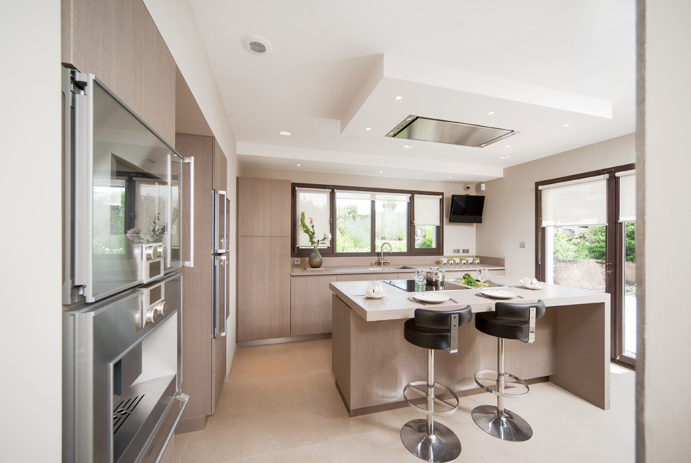 Medium sized modern galley kitchen in Lyon with a submerged sink, quartz worktops, stainless steel appliances, an island, flat-panel cabinets, light wood cabinets, beige floors and beige worktops.