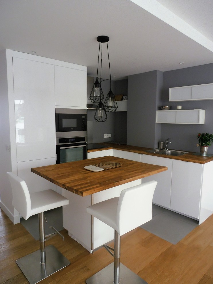 Idéer för att renovera ett litet funkis kök, med vita skåp, träbänkskiva, integrerade vitvaror, klinkergolv i keramik och en köksö