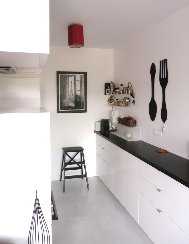 Idée de décoration pour une petite cuisine américaine parallèle et encastrable design avec des portes de placard blanches, un plan de travail en stratifié, une crédence blanche et parquet peint.