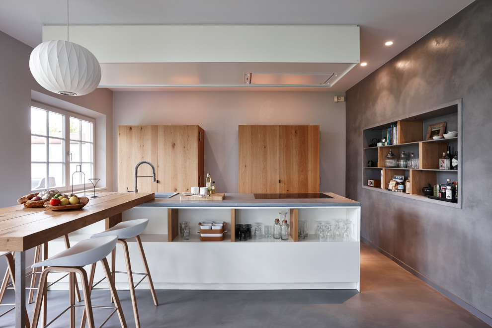 Große, Zweizeilige Moderne Wohnküche mit hellbraunen Holzschränken, Betonarbeitsplatte, Betonboden, zwei Kücheninseln, Einbauwaschbecken und offenen Schränken in Grenoble