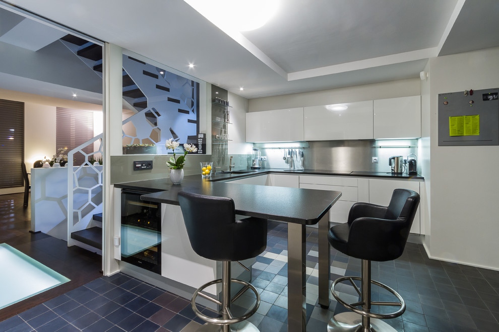Immagine di una grande cucina design con ante lisce, ante bianche, paraspruzzi a effetto metallico e penisola