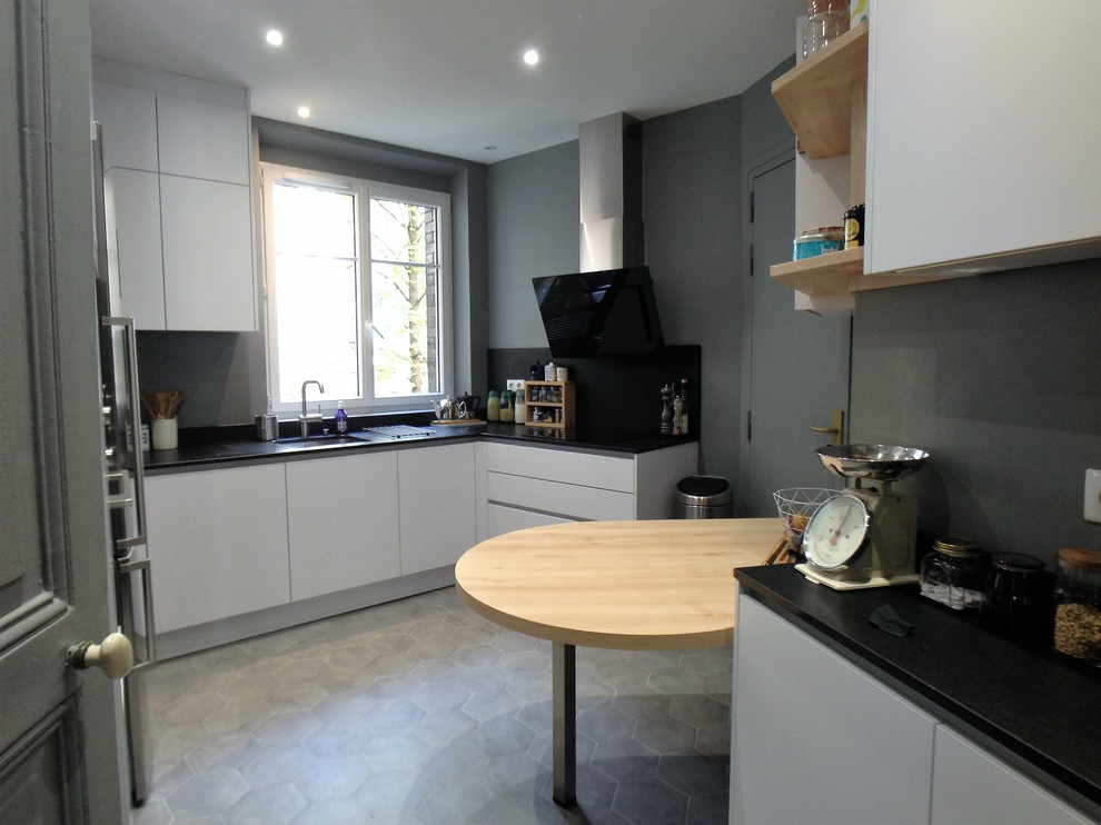 This is an example of a contemporary u-shaped enclosed kitchen in Paris with white cabinets, granite worktops, integrated appliances, cement flooring and grey floors.