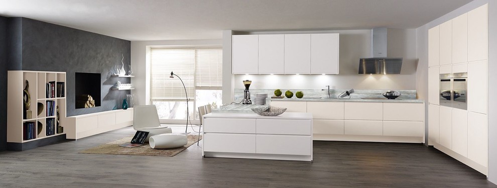 Modern inredning av ett mycket stort kök med öppen planlösning, med vita skåp, bänkskiva i onyx, grått stänkskydd, integrerade vitvaror, laminatgolv och brunt golv