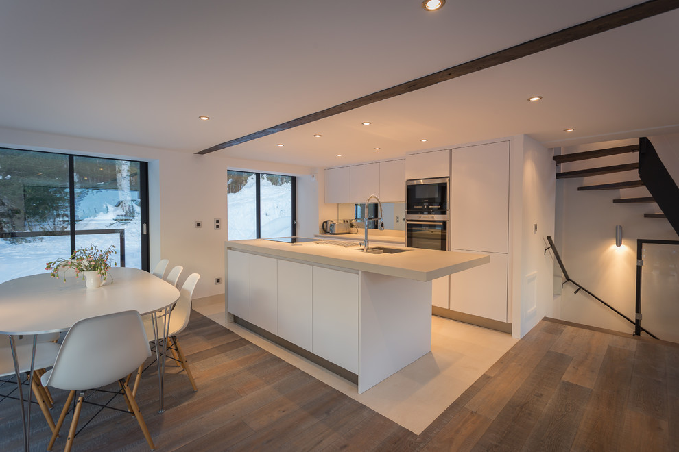 Cette photo montre une cuisine ouverte parallèle tendance de taille moyenne avec des portes de placard blanches et îlot.