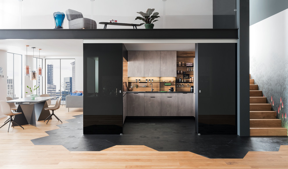 Идея дизайна: п-образная кухня в стиле модернизм с накладной мойкой, плоскими фасадами, серыми фасадами, бежевым фартуком, фартуком из дерева, полуостровом, черным полом, черной столешницей и красивой плиткой
