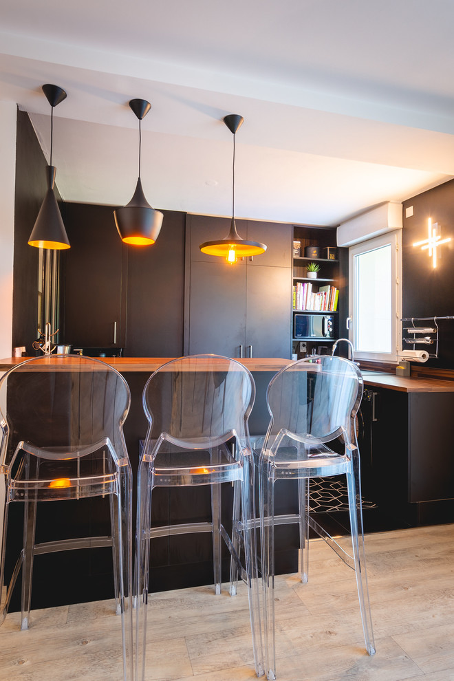 パリにある小さなモダンスタイルのおしゃれなキッチン (シングルシンク、インセット扉のキャビネット、黒いキャビネット、木材カウンター、黒いキッチンパネル、木材のキッチンパネル、黒い調理設備、淡色無垢フローリング、ベージュの床、ベージュのキッチンカウンター) の写真