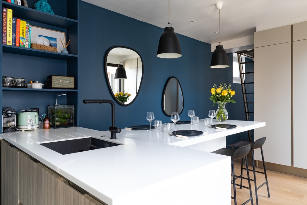 Foto di una cucina design con lavello sottopiano, parquet chiaro, penisola, pavimento beige e top bianco