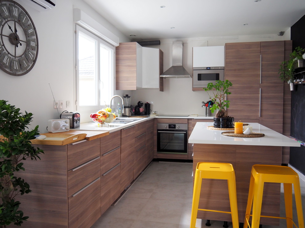 Diseño de cocinas en L contemporánea con fregadero encastrado, armarios con paneles lisos, puertas de armario de madera en tonos medios, electrodomésticos de acero inoxidable y una isla