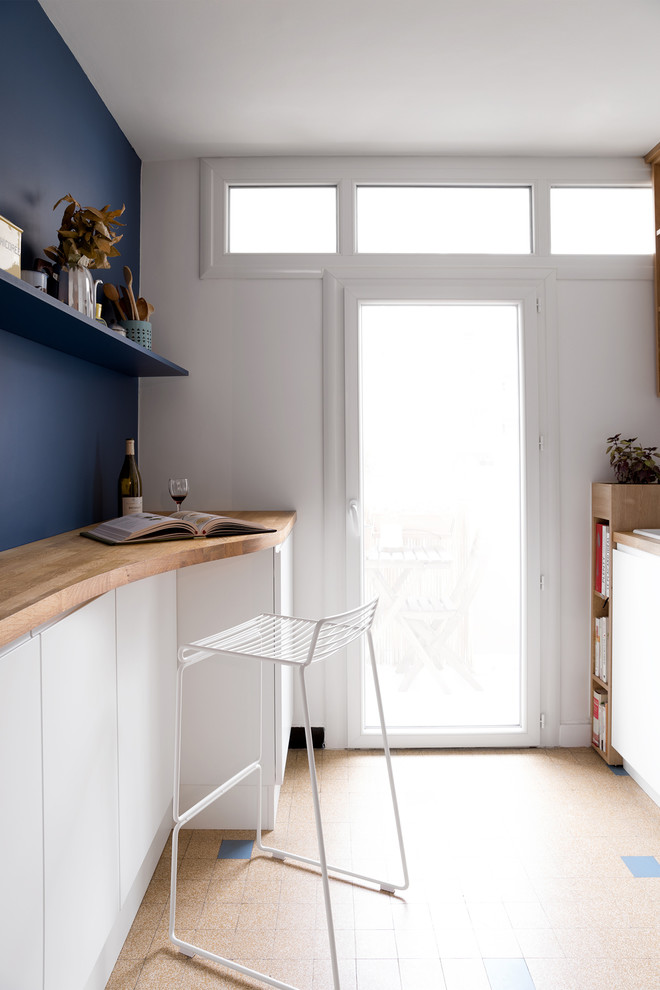 リヨンにあるお手頃価格の小さな北欧スタイルのおしゃれなキッチン (白いキャビネット、木材カウンター、青いキッチンパネル、セラミックタイルの床) の写真