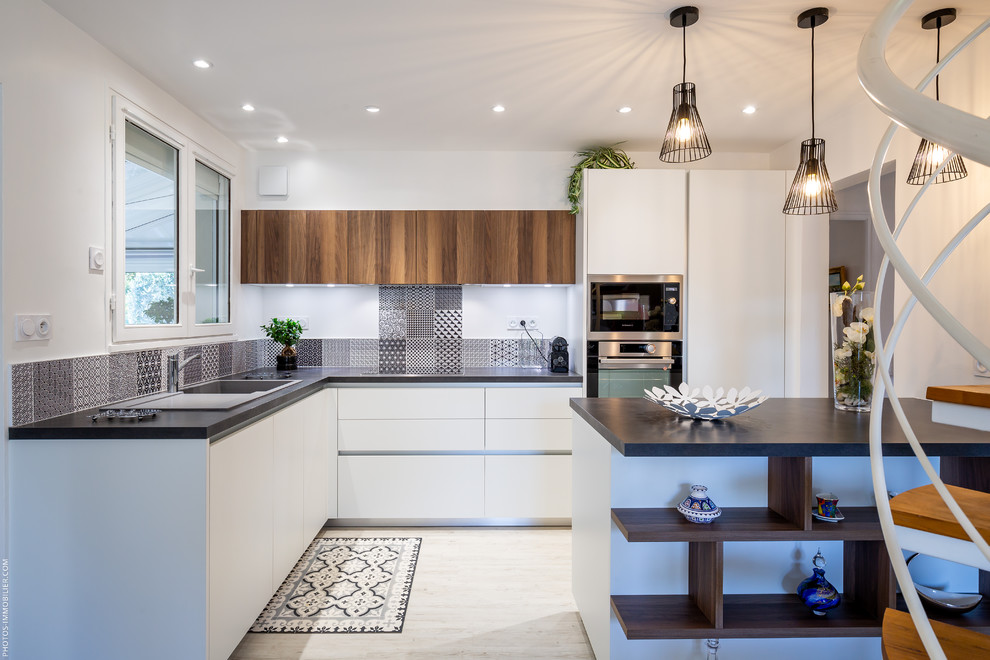 Immagine di una cucina nordica di medie dimensioni con ante lisce, ante bianche, paraspruzzi multicolore, paraspruzzi con piastrelle di cemento, elettrodomestici neri, pavimento beige e top nero