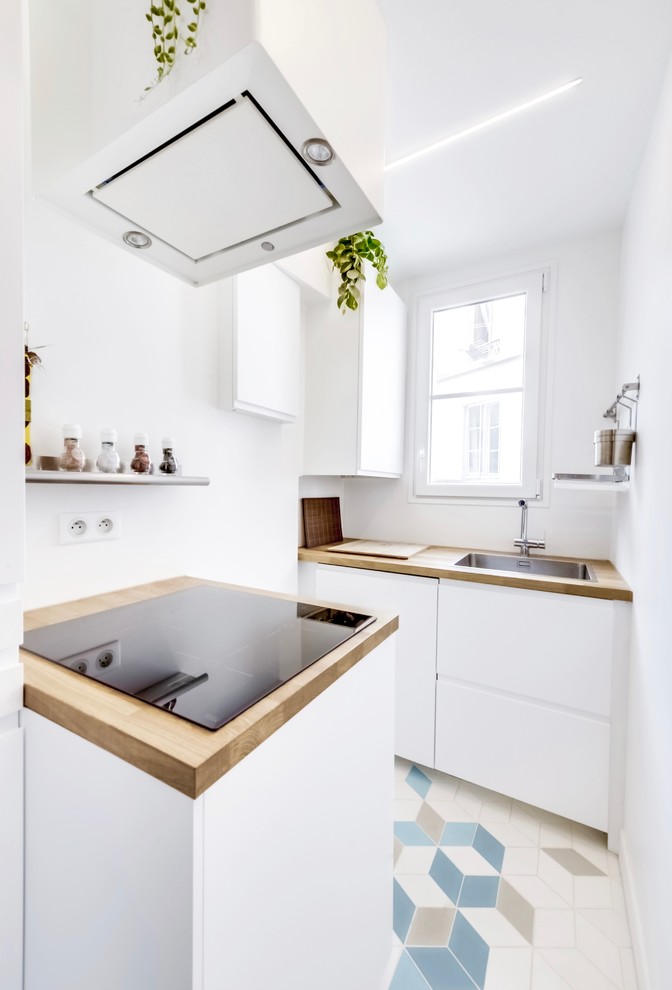 Bild på ett mellanstort nordiskt kök, med en enkel diskho, luckor med profilerade fronter, vita skåp, träbänkskiva, vitt stänkskydd, fönster som stänkskydd, rostfria vitvaror och klinkergolv i keramik
